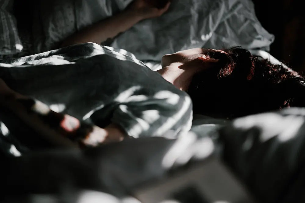 Frau schläft im Bett mit Sonnenstrahlen