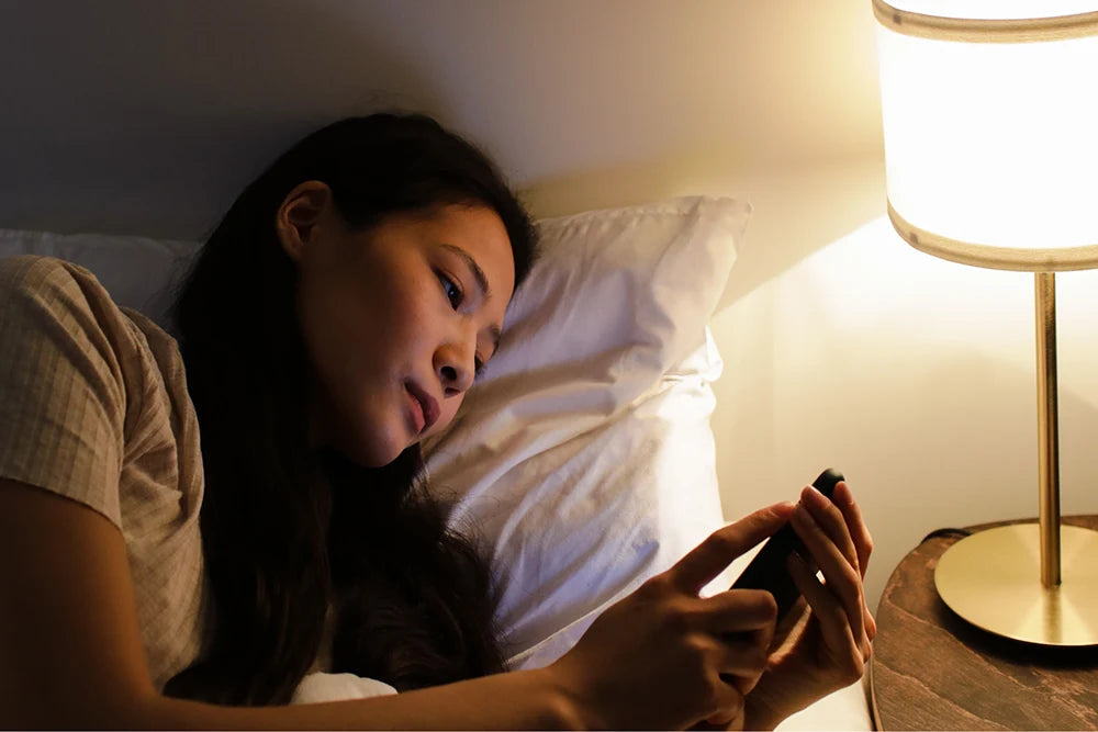Frau liest im Bett auf dem Handy